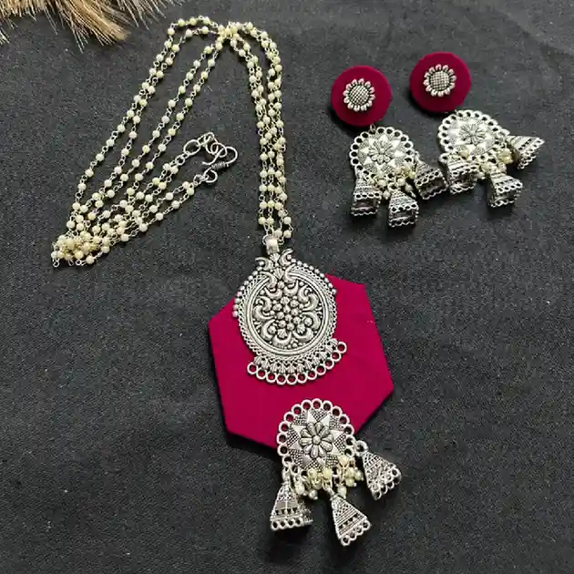 Rani pink fabric oxidised silver necklace set with intricate round pendant, multi-layer pearl chain and matching statement earrings displayed on a dark background