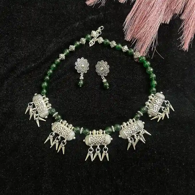 Handcrafted emerald green faceted onyx bead necklace featuring five oxidized silver tribal drum charms with dangles and matching floral drop earrings by Itsy Bitsy Kolkata.