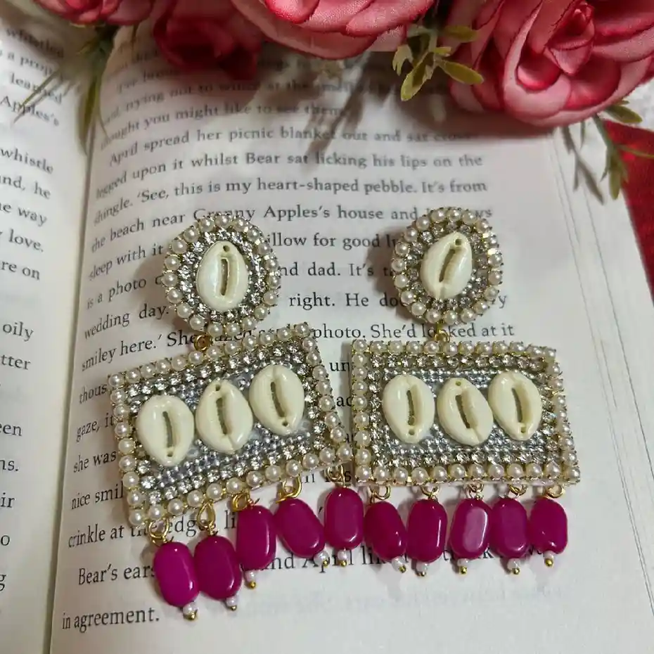Handcrafted rectangular statement earrings featuring white cowrie shells, intricate pearl beadwork, and vibrant magenta drop beads from Itsy Bitsy Kolkata.