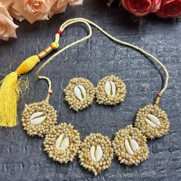Handcrafted choker necklace and earring set featuring white pearls and natural cowrie shells on a grey background.