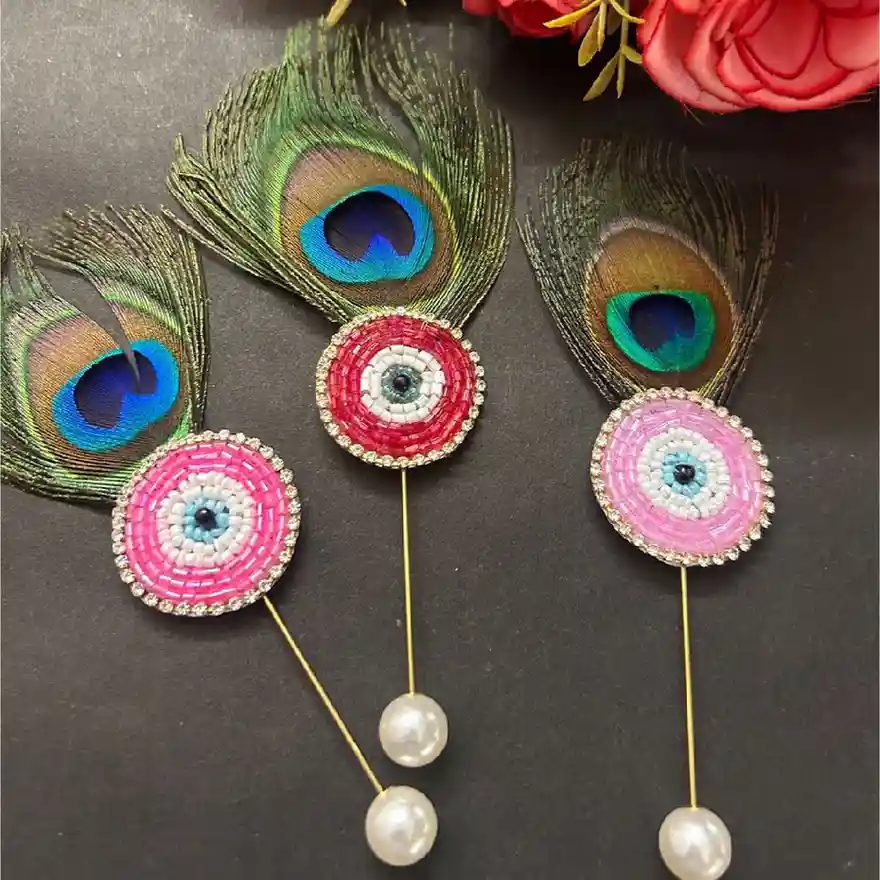 Hand-beaded evil eye brooches in pink and red with real peacock feathers and pearl stoppers, handcrafted by ItsyBitsy Kolkata.