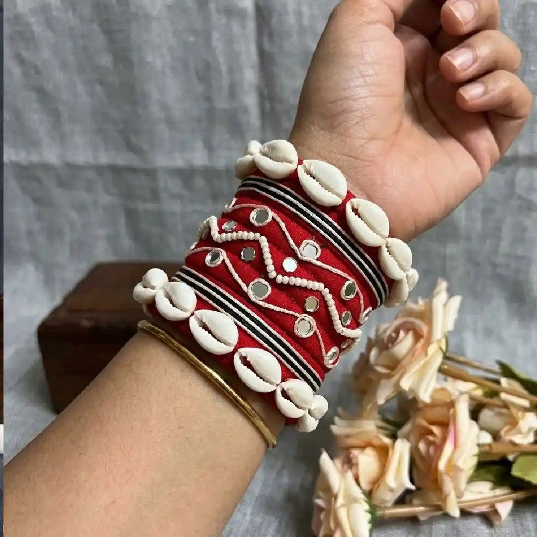 Traditional red silk thread bangle set for women featuring white cowrie shells, mirror work, and beaded zig-zag patterns, handcrafted by Itsy Bitsy Kolkata.
