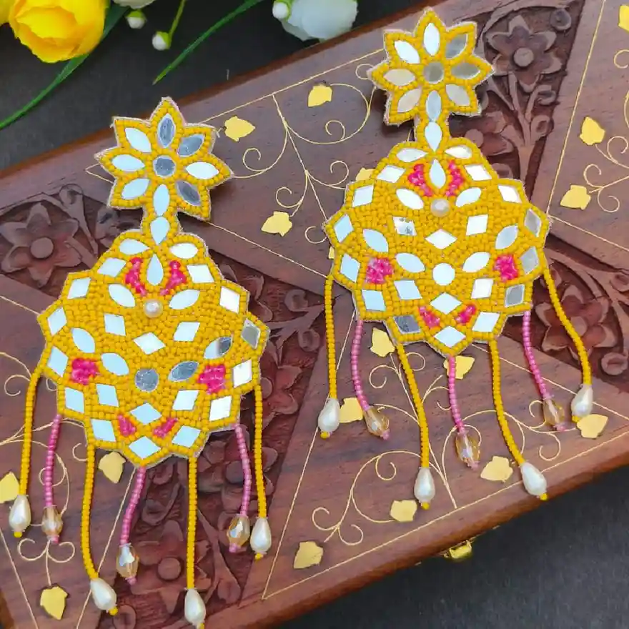 Handcrafted yellow seed bead statement earrings featuring intricate mirror work, pink accents, and hanging bead charms with pearl drops.