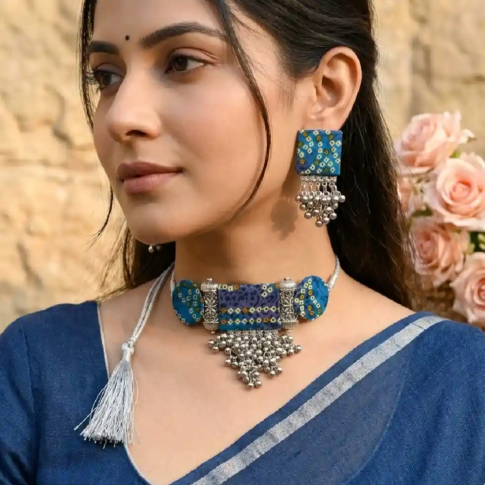 Model showcasing the indigo blue bandhani fabric choker and earrings from Itsy Bitsy Kolkata, styled with a traditional beige cotton saree in a cozy home setting.