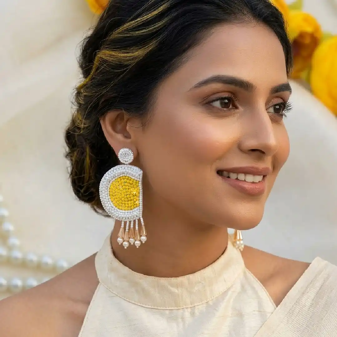Model wearing handcrafted yellow and white beaded half-moon earrings with a vibrant yellow silk saree – Itsy Bitsy Kolkata