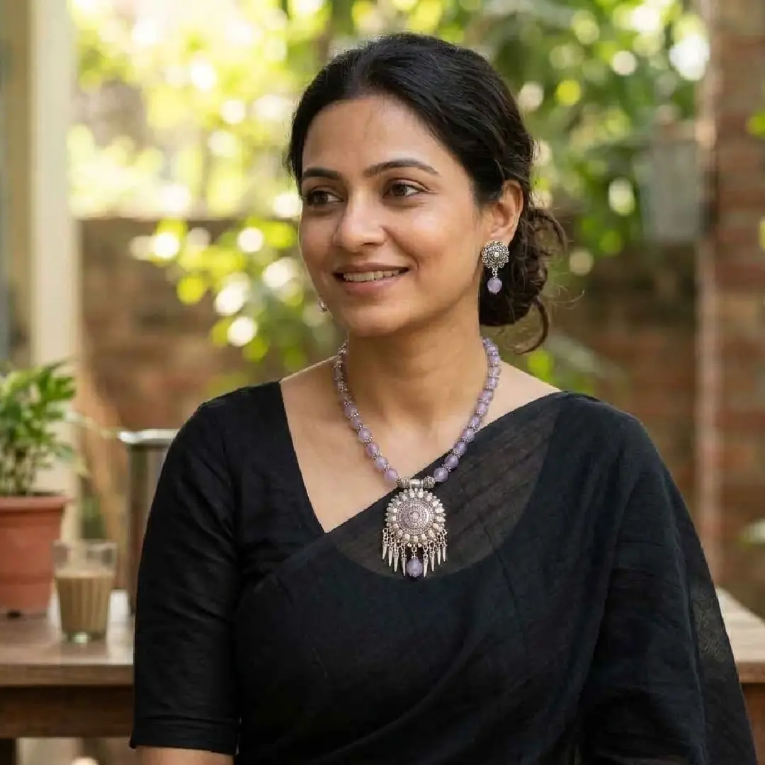 lifestyle model photo for itsybitsykolkata.com featuring a woman in a classic black cotton saree wearing a handcrafted lavender onyx and oxidized silver beaded necklace and matching floral earrings in a natural daily life setting.