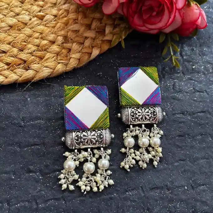 Artisanal square earrings featuring central mirrors wrapped in multi-colored silk threads, finished with oxidised silver spacers and cascading white pearl clusters.