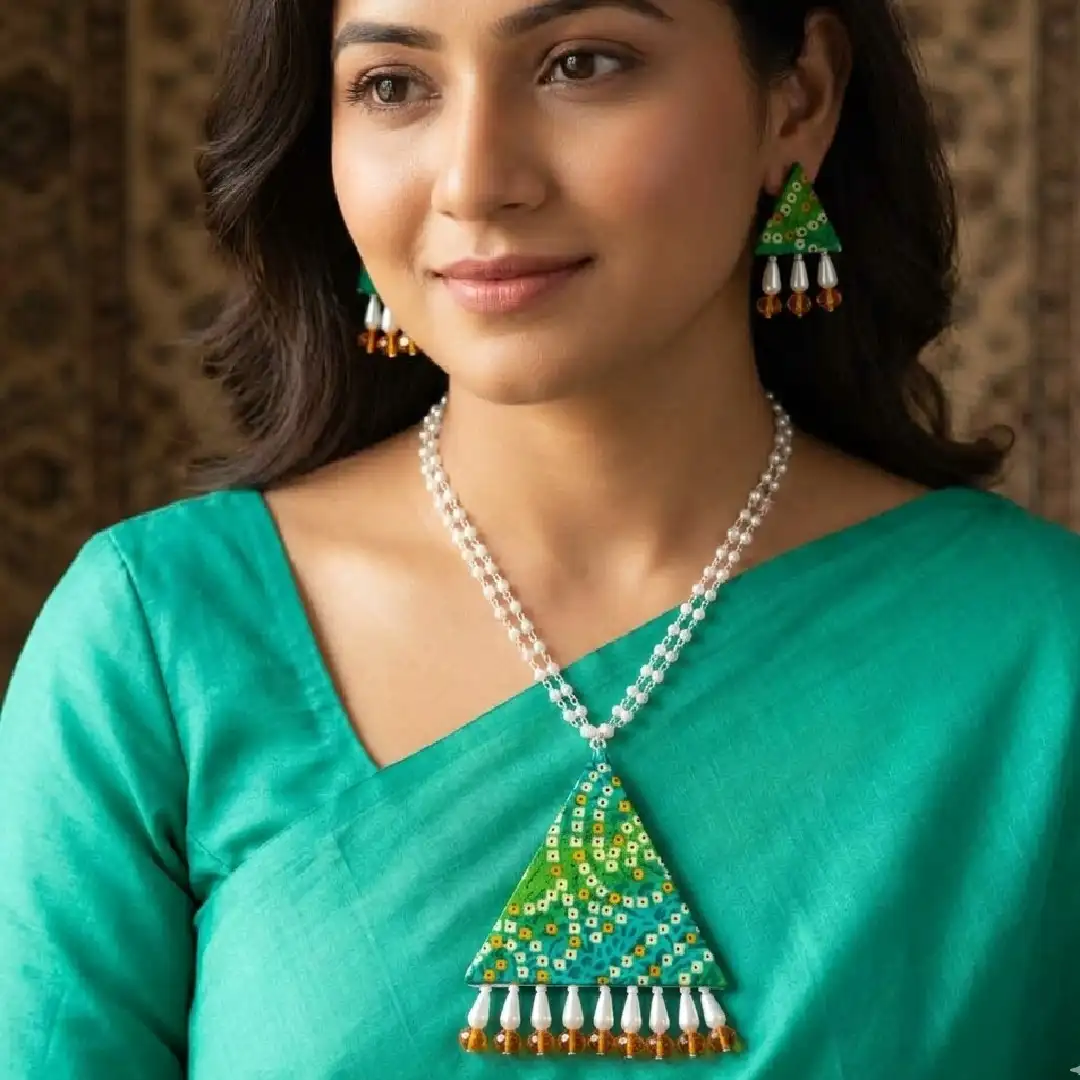 A model wearing the handcrafted green Bandhani fabric triangular pendant necklace and matching earrings with white pearls and orange beads from Itsy Bitsy Kolkata, styled with an ethnic outfit.