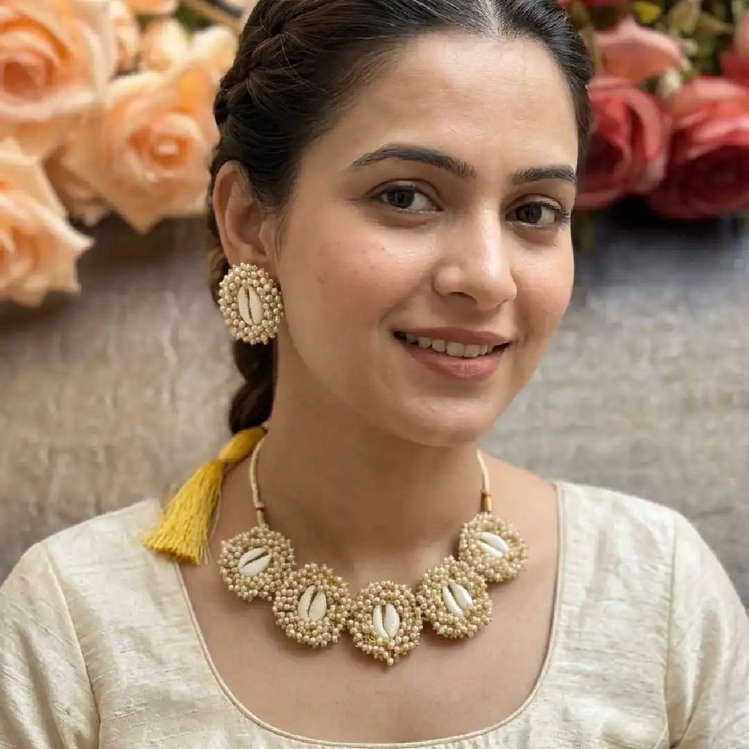 A model showcasing the handcrafted cowrie shell and pearl choker necklace with matching earrings from Itsy Bitsy Kolkata, styled for a festive Haldi ceremony.