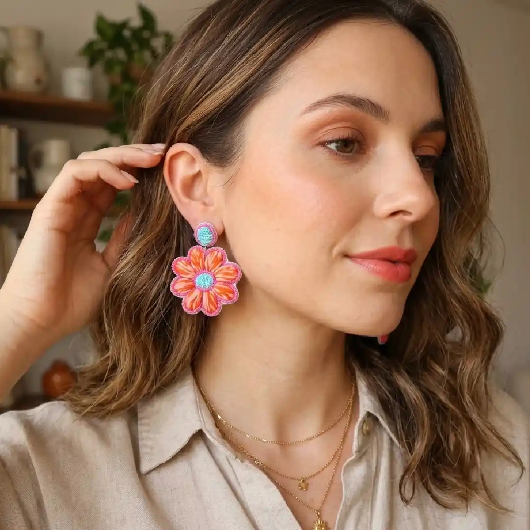 Lifestyle shot of a model wearing handcrafted orange and pink beaded floral earrings from Itsy Bitzy Kolkata, styled with a modern pastel cotton kurti in a sunlit daily background.