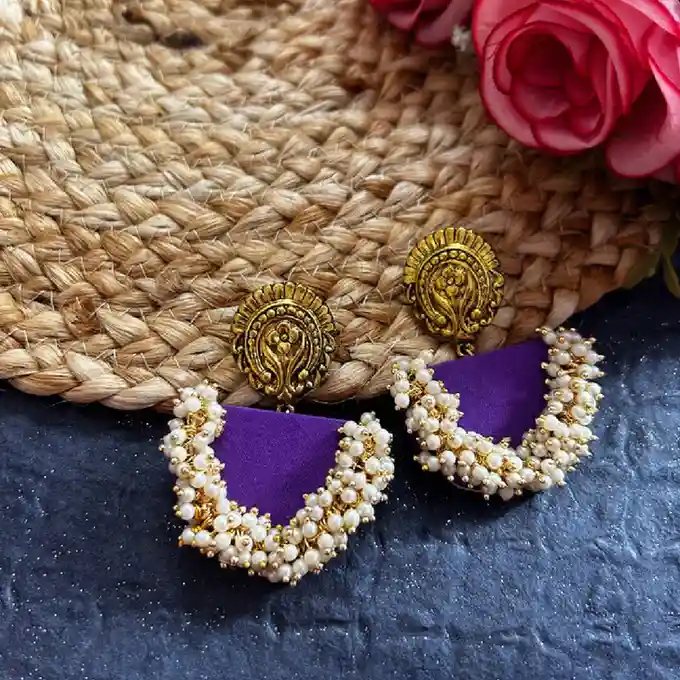 A pair of vibrant yellow circular fabric earrings featuring a central star-shaped mirror motif, a border of square mirrors, and dangling golden engraved coins on a textured dark background.