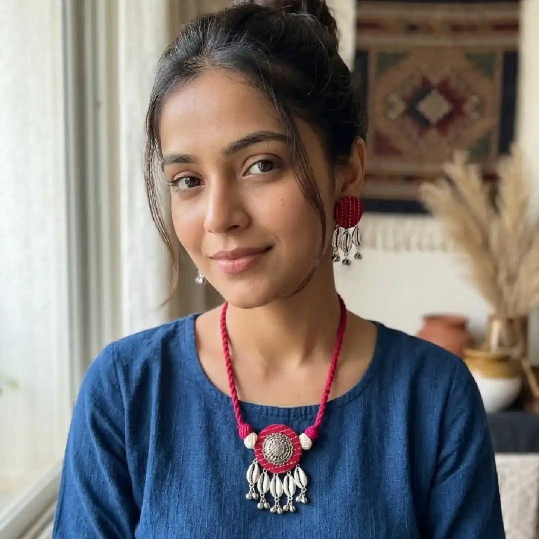 Model showcasing a handcrafted rani pink fabric necklace from Itsy Bitzy Kolkata, featuring an oxidised silver mandala pendant with silver shell charms and matching earrings, styled with a simple navy blue cotton kurta.
