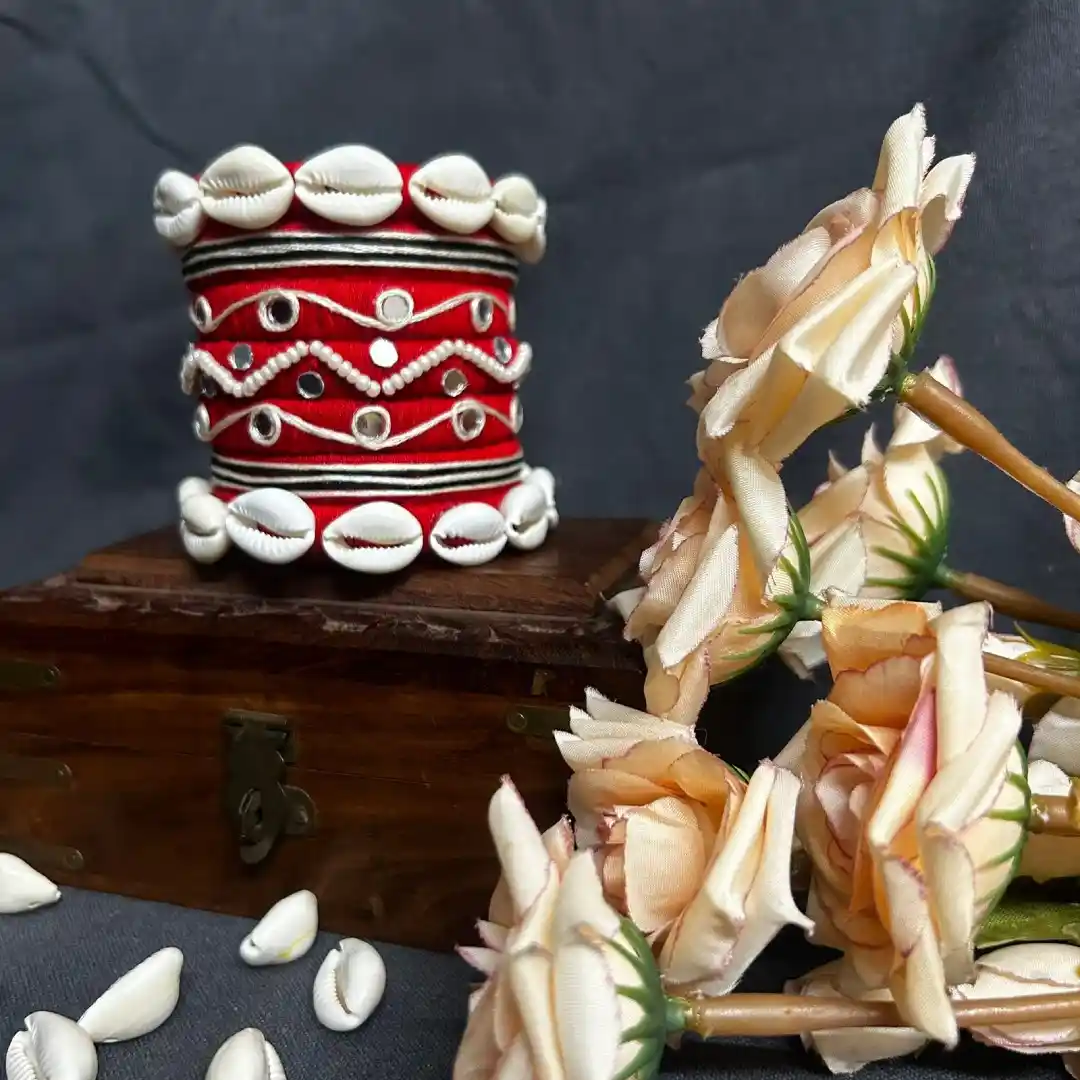 Handcrafted red silk thread bangles with white cowrie shells and mirror work for festive wear.