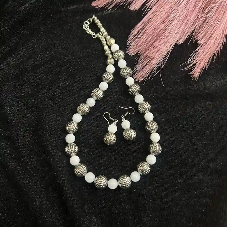 Handcrafted white onyx bead necklace with intricately carved oxidized silver metal beads and matching drop earrings by Itsy Bitsy Kolkata.