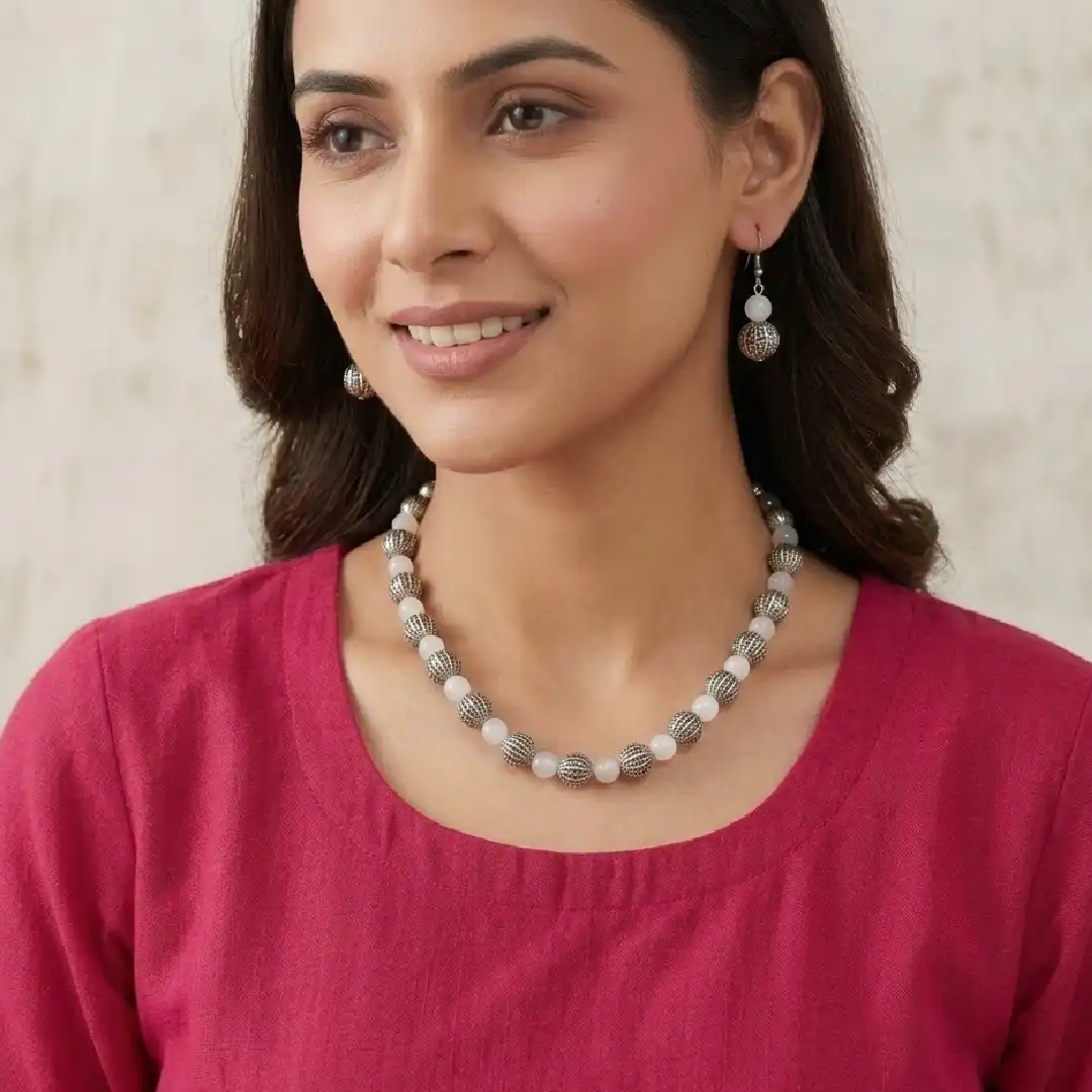 lifestyle model photo for itsybitsykolkata.com featuring a woman in a rani pink cotton kurta wearing a continuous handcrafted white onyx and oxidized silver beaded necklace (without a central pendant) and matching earrings.