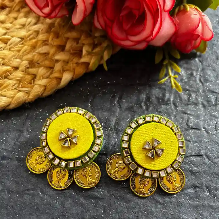 A pair of vibrant purple fabric chandbali earrings featuring ornate antique gold-finish floral studs and a thick border of intricately woven white seed pearls.