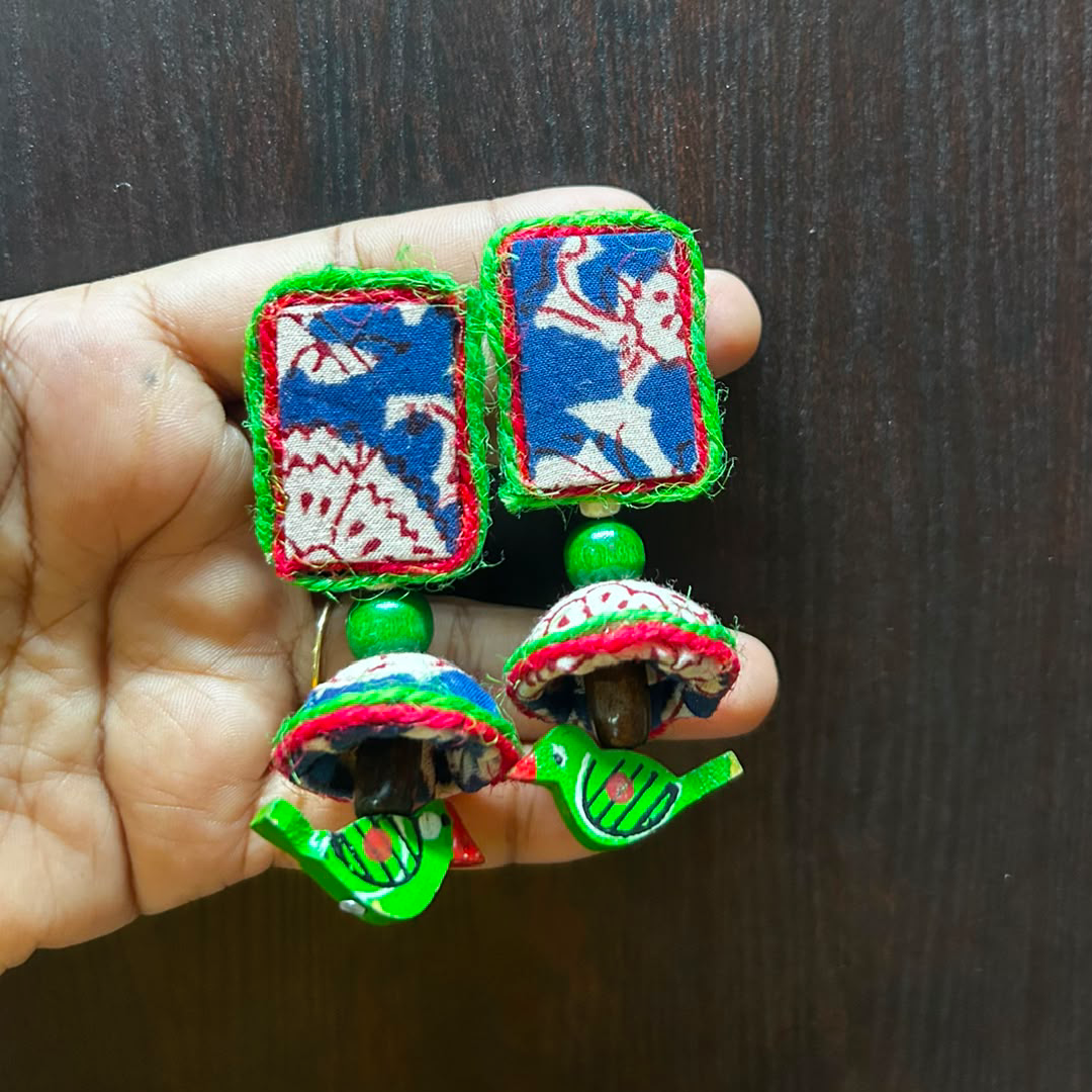 Handmade ethnic jhumka earrings featuring square blue and white Kalamkari fabric studs, green beads, and matching patterned fabric drops with a tiny green bird accent